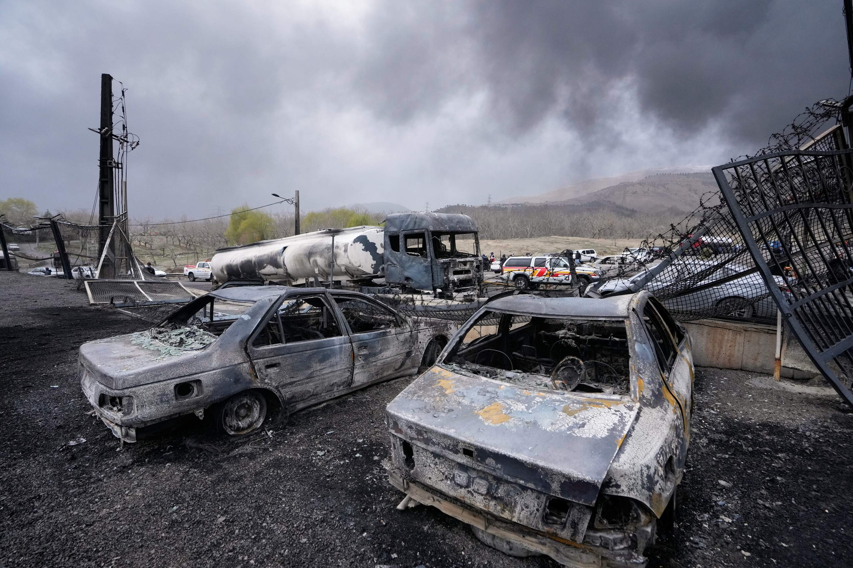Burned vehicles sit near an oil storage facility struck by a U.S.-Israeli attack late Saturday as a thick plume of smoke rises in Tehran, Iran, Sunday, March 8, 2026. (Vahid Salemi/AP)