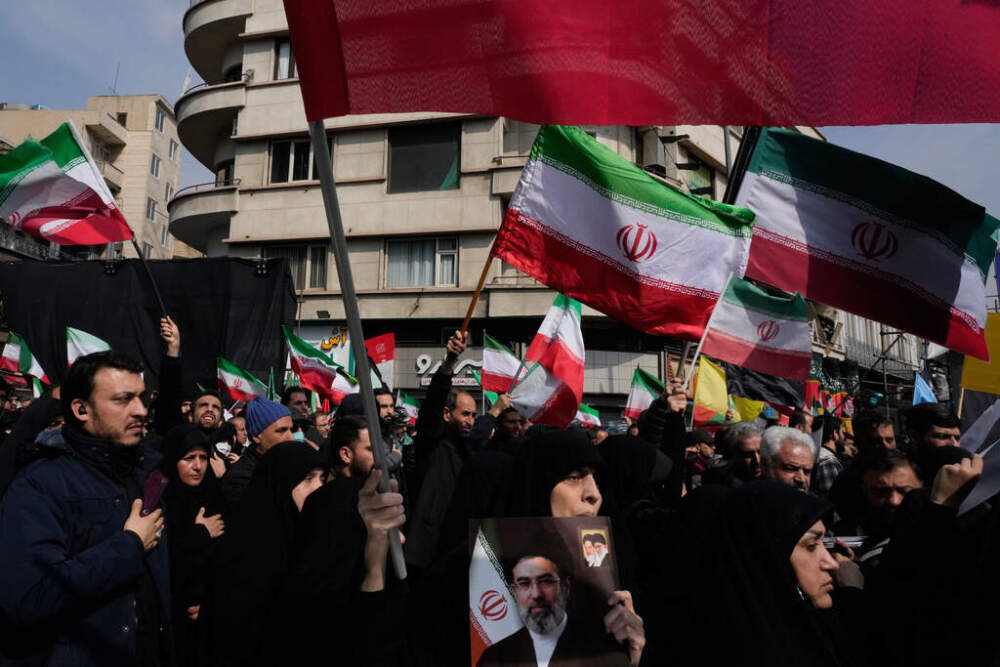 Mourners wave Iranian flags during the funeral procession for senior Iranian military officials and civilians killed during the U.S.-Israel campaign in Tehran, Iran, on March 11. (Vahid Salemi/ AP)