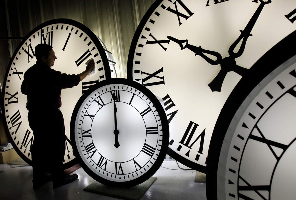 A man cleans the face of an 84-inch Wegman clock in Medfield, Massachusetts in 2008. (Elise Amendola/AP file)