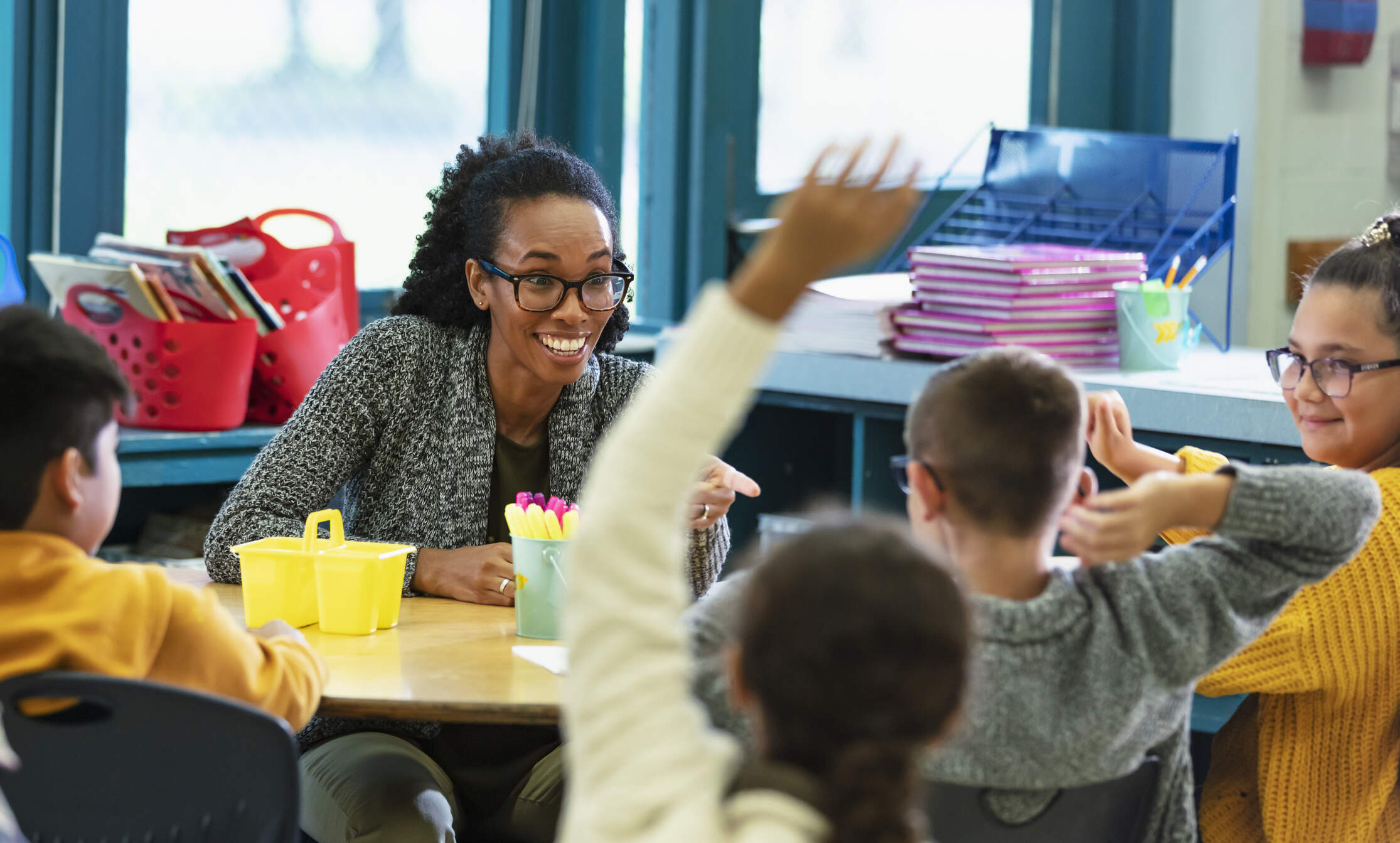 A multiracial group of elementary students in class raising their hands to answer a question. (Getty Images)