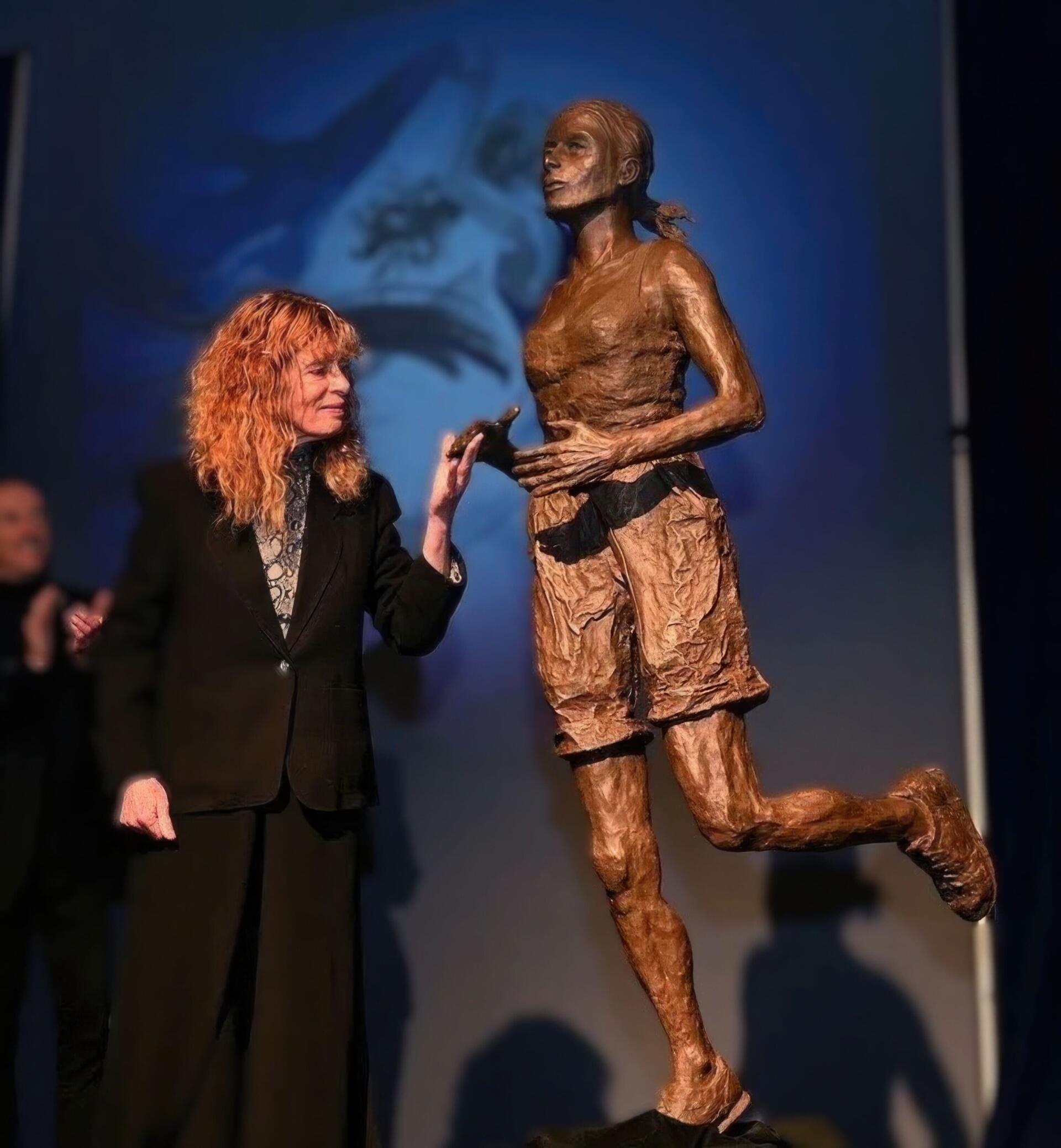 Bobbi Gibb stands next to a statue of herself that has been installed near the state of the Boston Marathon.