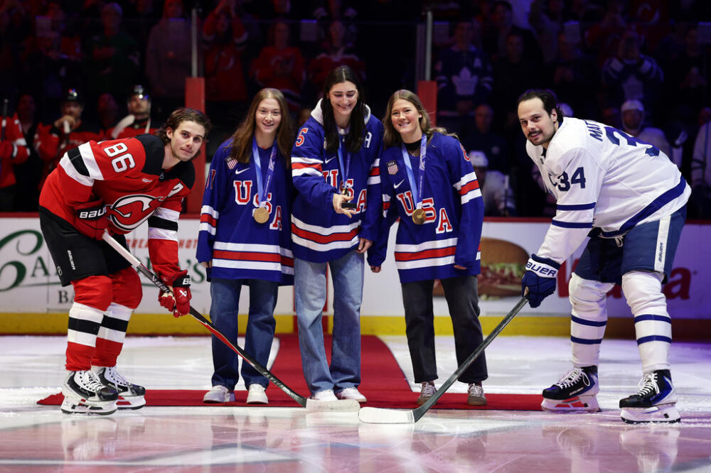 United States women's gold medal hockey players, center left to right, Aerin Frankel, Megan Keller and Haley Winn with New Jersey Devils center Jack Hughes (86) and Toronto Maple Leafs center Auston Matthews (34) for a ceremonial puck drop before an NHL hockey game Wednesday, March 4, 2026, in Newark, N.J. (Adam Hunger/AP)