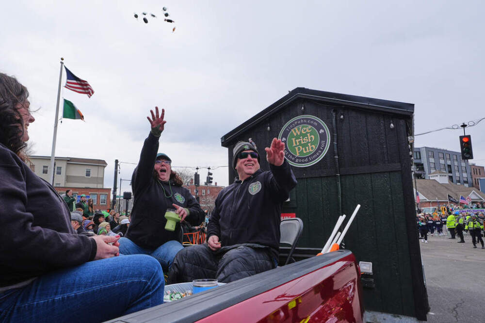 Dena Taylor and Tony DiDonato, right, toss candy to spectators while riding in a truck hauling the "Wee Irish Pub" during the annual St. Patrick's Day parade through Southie, Sunday, March 15, 2026. (Charles Krupa/AP)