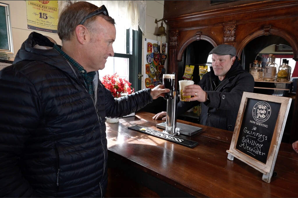 Mark Cote, left, toasts Matt Taylor after receiving delivery of a rented tiny pub for an early St. Patrick's Day party, Friday, March 13, 2026, in Andover, Mass. (Robert F. Bukaty/AP)