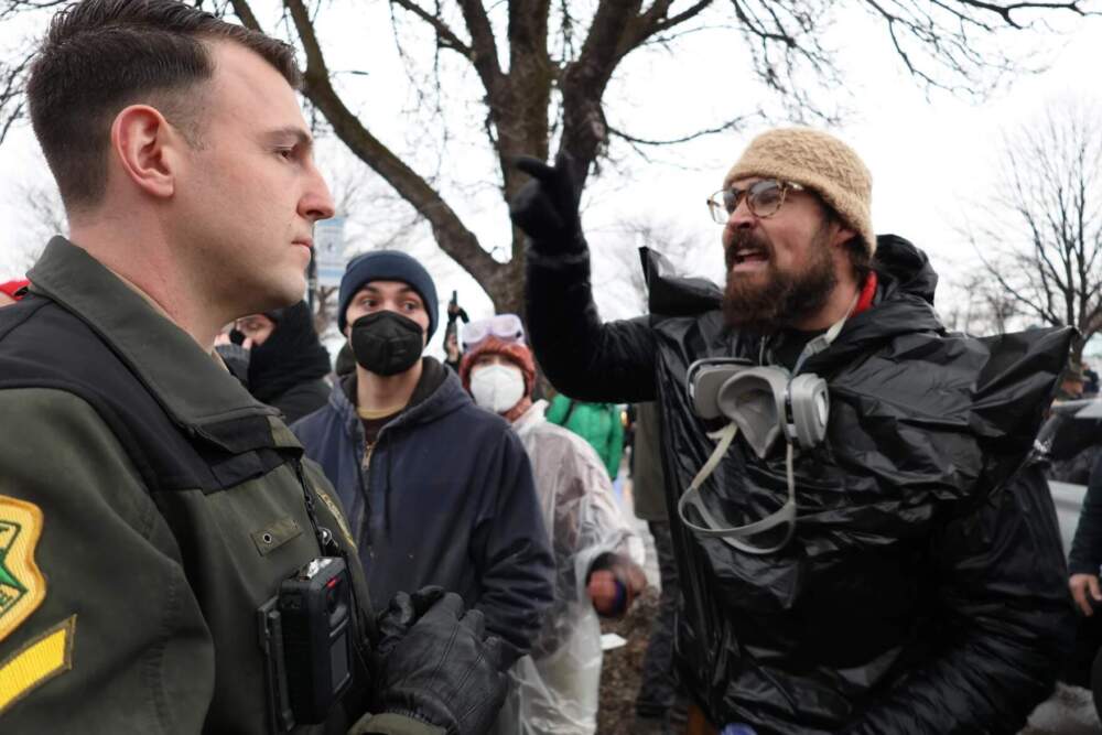Protesters confront Vermont State Police officers outside a South Burlington home after ICE officers entered it to make arrests. (Zoe McDonald/Vermont Public)