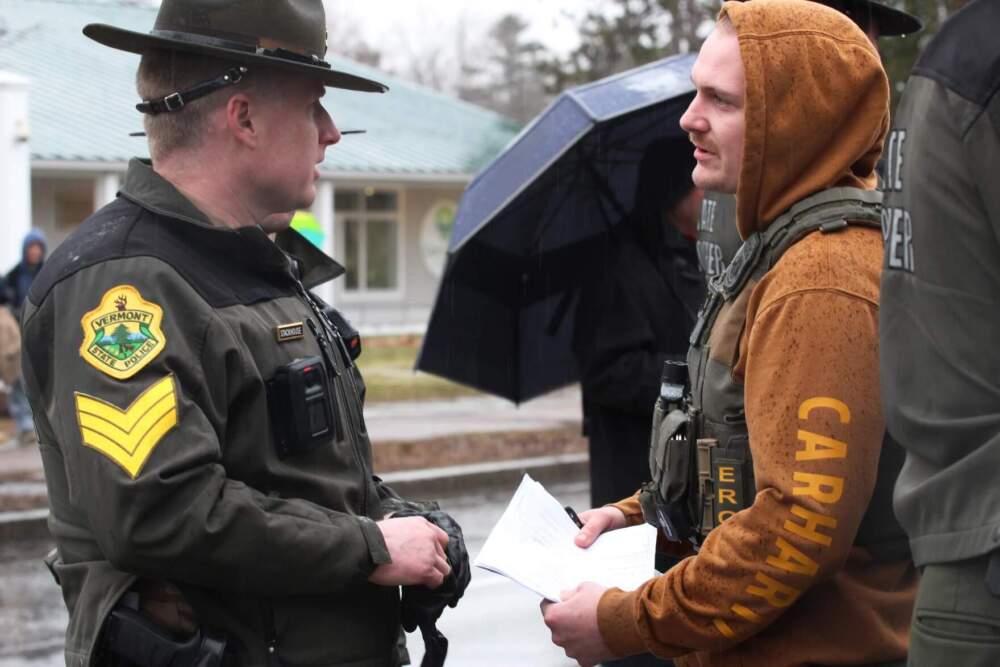 An ICE officer holding a warrant speaks to a Vermont State Police officer on Dorset Street. (Zoe McDonald/Vermont Public)