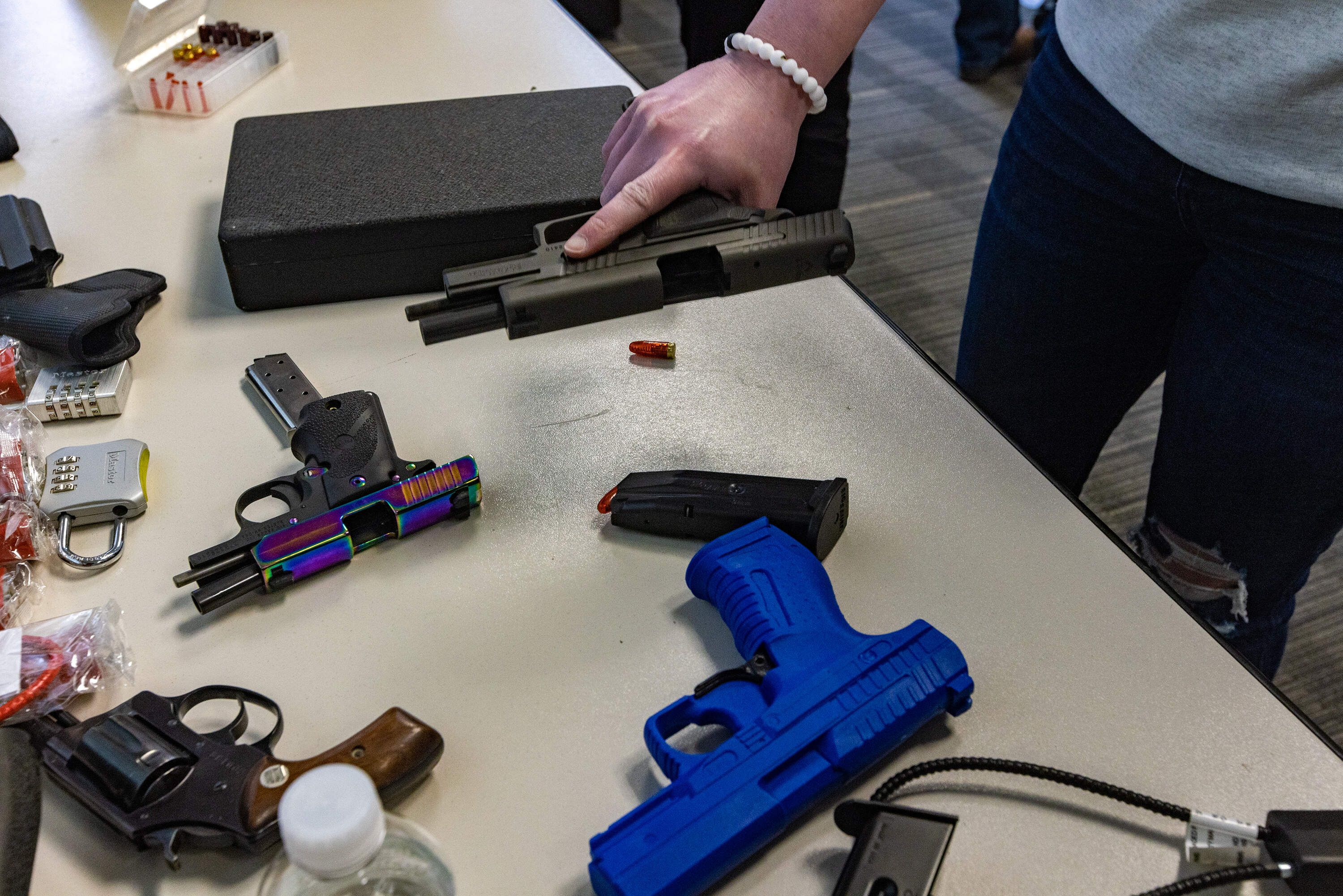 A person picks up a 9mm pistol during a gun safety class at William James College in 2023.
