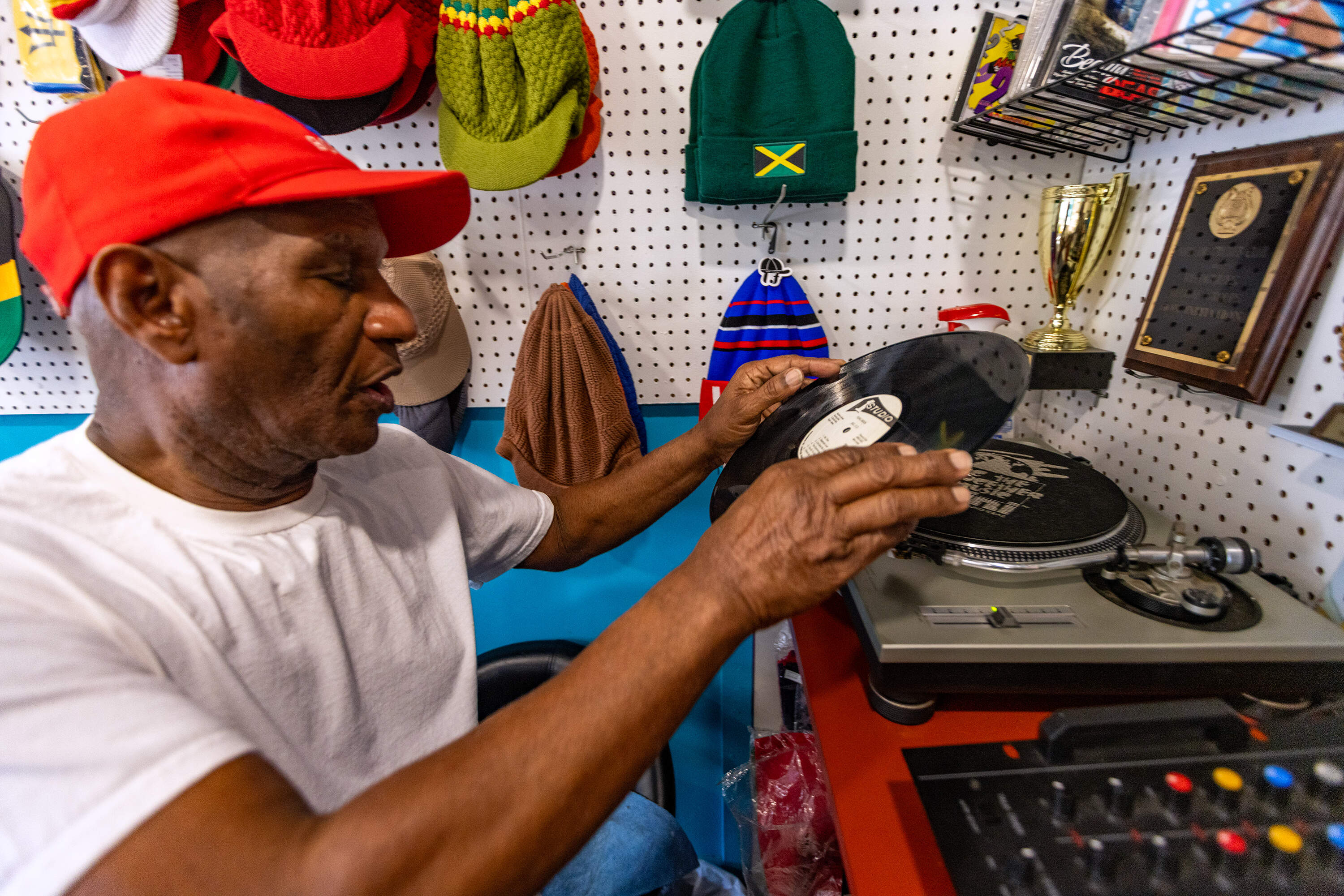 Leroy Webb places an album by Bob Andy onto the turntable to play at Taurus Records in Mattapan. (Jesse Costa/WBUR)