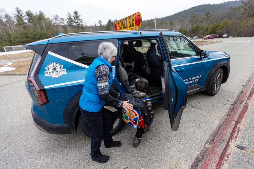 School bus driver Lois Wells assists a child to get into the electric powered vehicle. (Jesse Costa/WBUR)