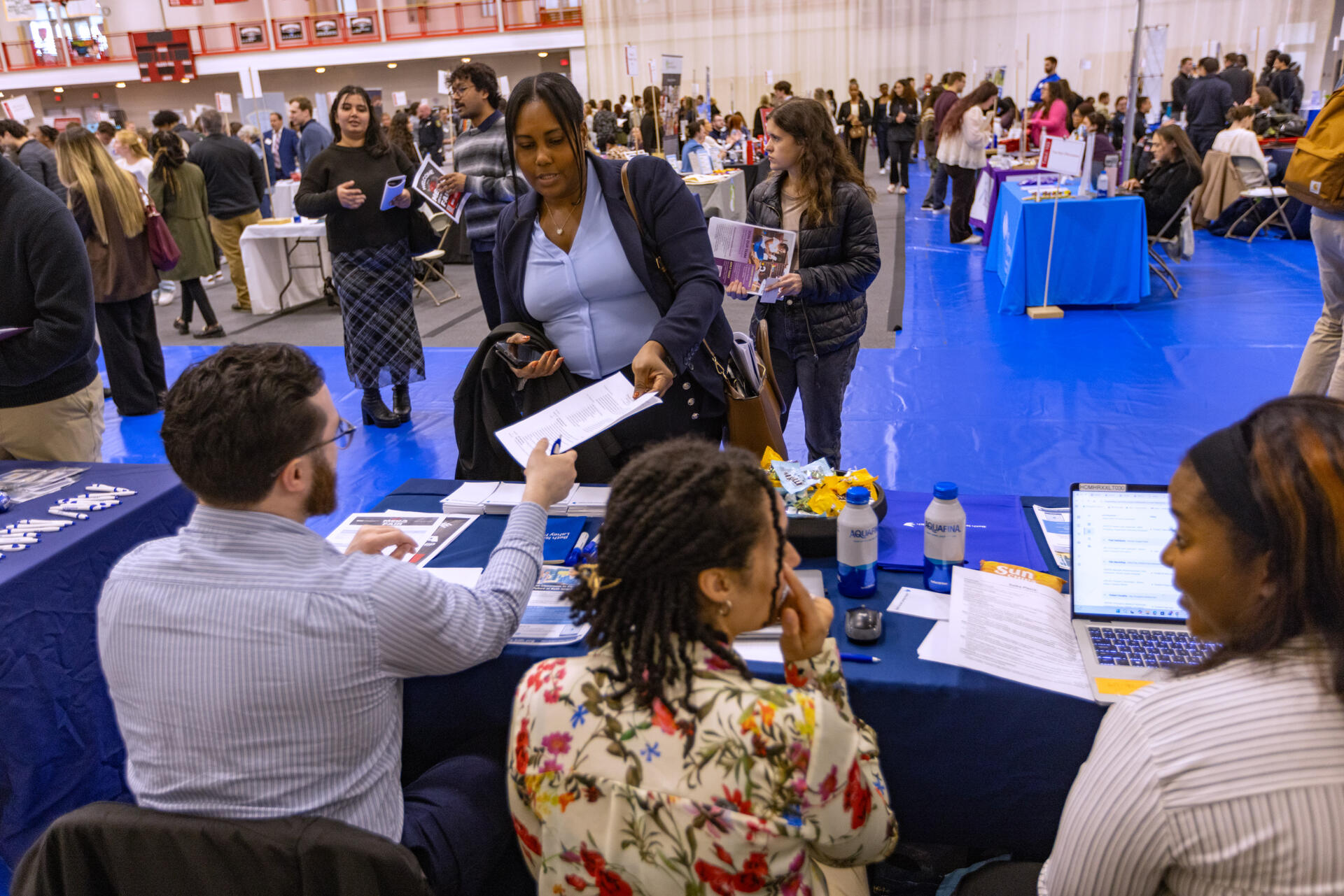 Senior Sherly Coriolan hands her resume to an representative at the Beth Israel Lahey Clinic table during the Bridgewater State University. (Jesse Costa/WBUR)