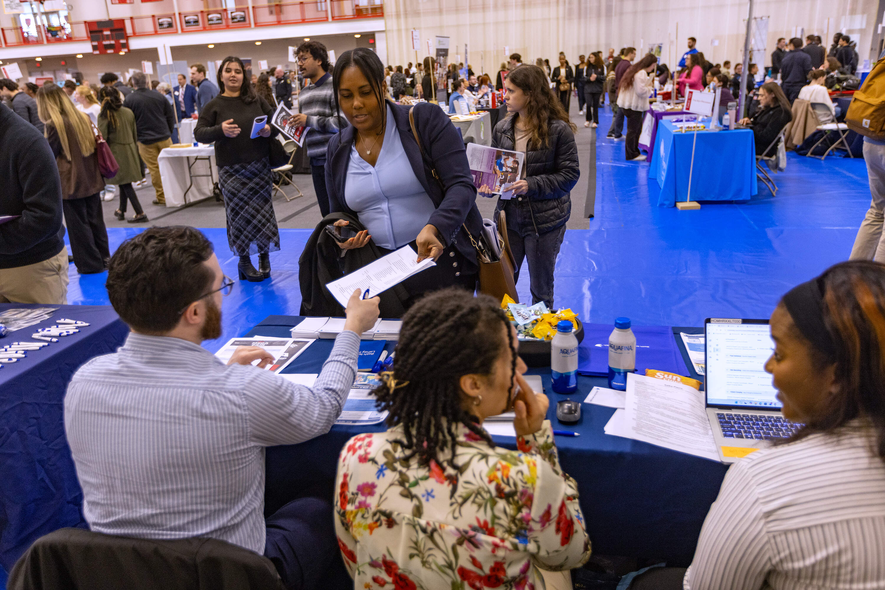Senior Sherly Coriolan hands her resume to an representative at the Beth Israel Lahey Clinic table during the Bridgewater State University. (Jesse Costa/WBUR)
