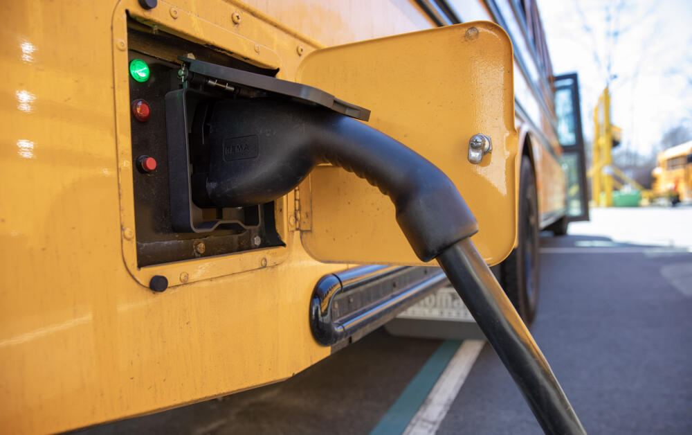 An electric bus charges in the Beverly, Mass., school bus parking lot. (Robin Lubbock/ WBUR)
