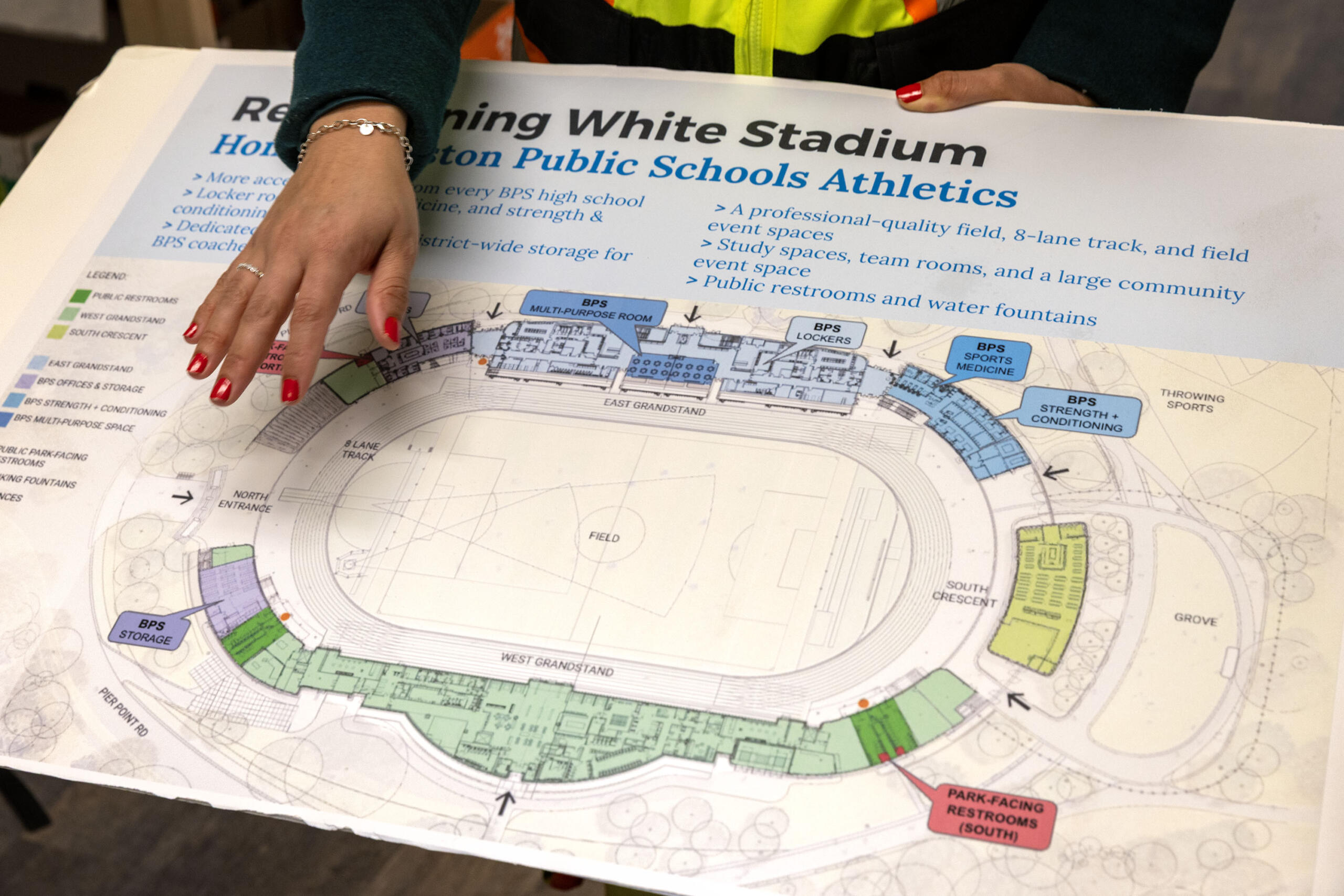 Diana Fernandez Bibeau, deputy chief of urban design at the Boston Planning Department, shows the layout for the new White Stadium to a group of visitors at the construction site. (Robin Lubbock/WBUR)