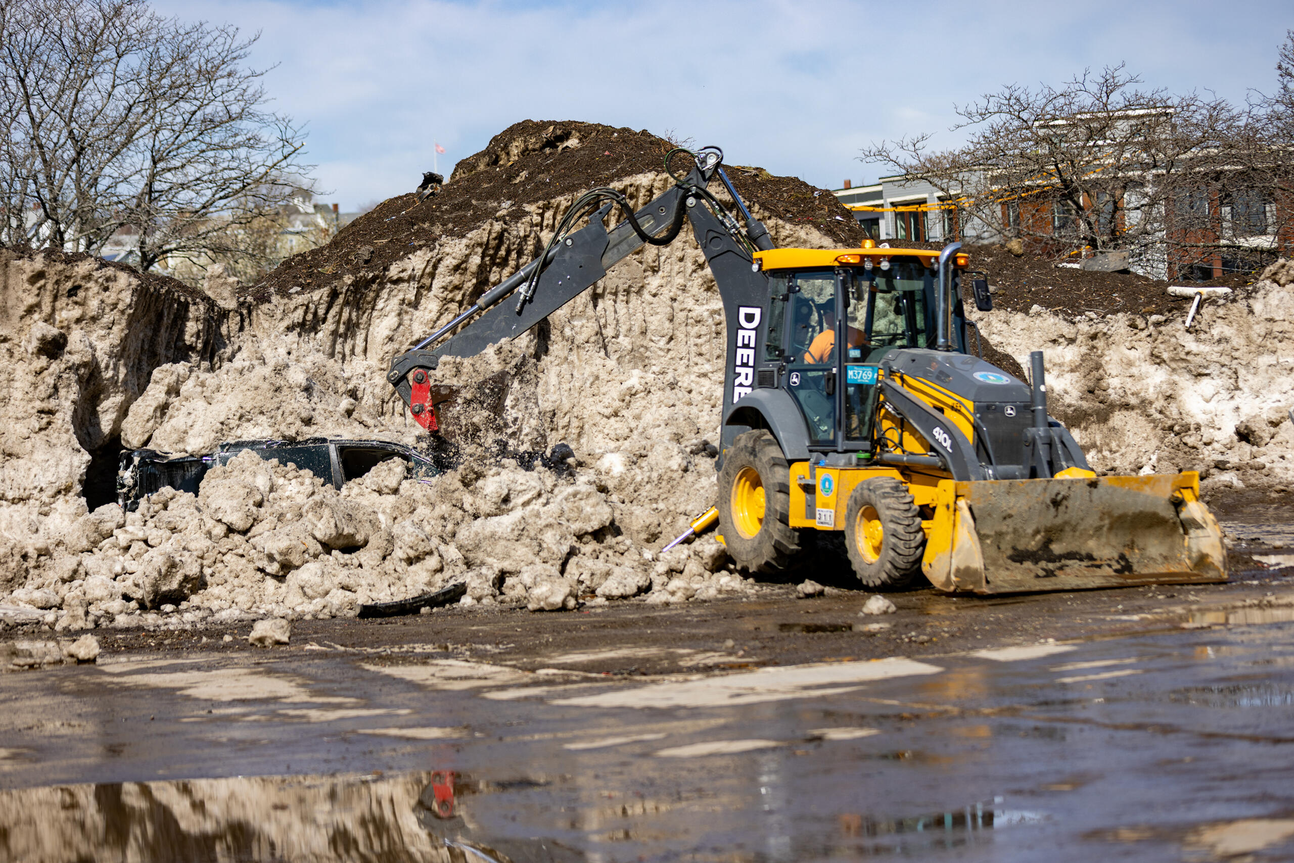 Somerville city workers unearth a city van from a massive snow pile in a vacant lot on Washington Street. 