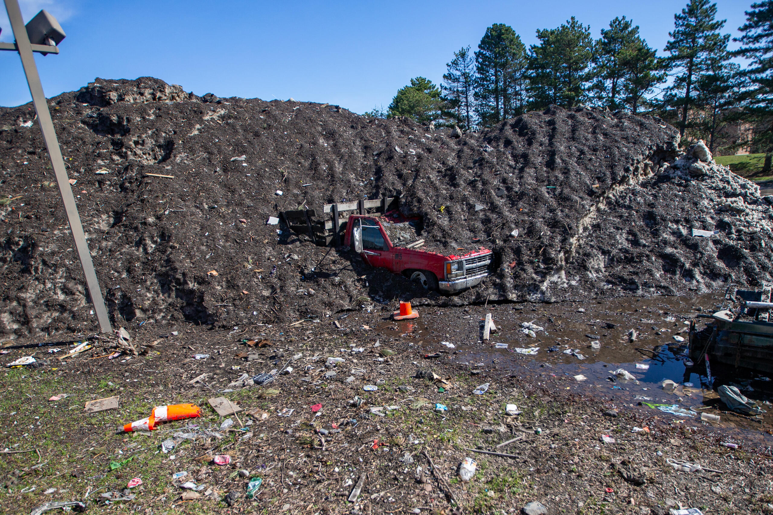 A truck sits partially buried under a massive snow pile in a vacant lot on Washington Street in Somerville.