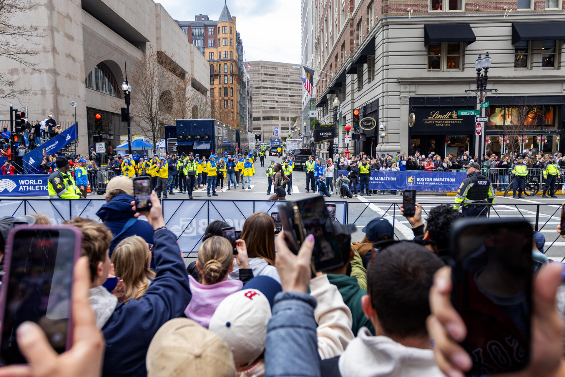Boston Marathon fans on Boylston Street cheer and raise their cell phones as Sharon Lokedi nears the finish line. (Jesse Costa/WBUR)