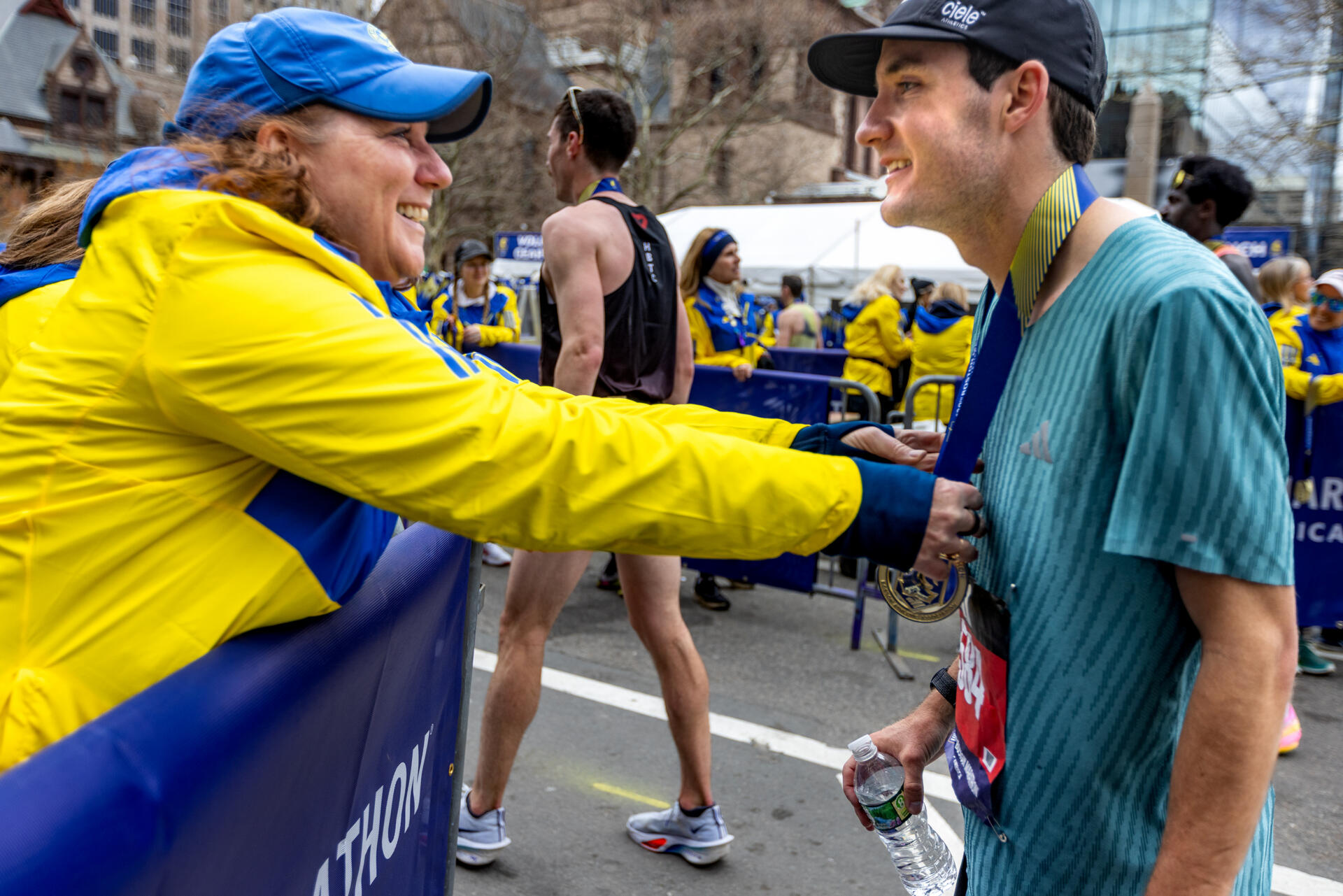 Conner Coughlin smiles as volunteer Colleen Faladeau gives him his medal after he finished the Boston Marathon. (Jesse Costa/WBUR)