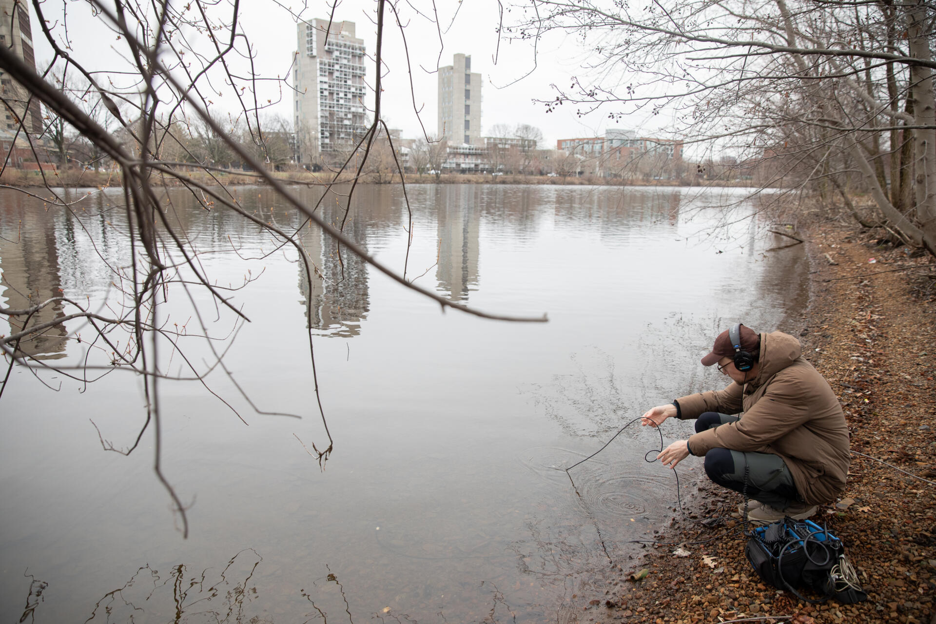 Artist and researcher Jacek Smolicki uses a hydrophone to record underwater sounds next to the Charles River in Cambridge. (Artemisia Luk/WBUR)