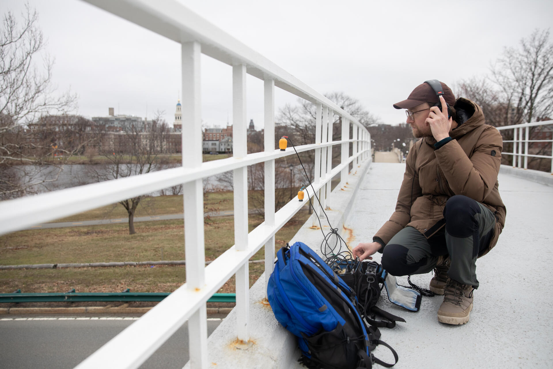 Artist and researcher Jacek Smolicki takes out his multi-channel sound field recorder on John W. Weeks Bridge in Cambridge. He uses a contact microphone to listen to vibrations on the railings of the bridge, created from the traffic below. (Artemisia Luk/WBUR)