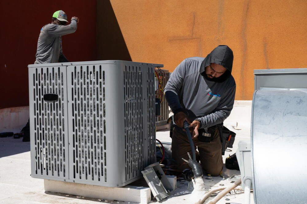 Two men install a new air conditioning unit alongside during record-breaking heat on Thursday, March 19 in Tempe, Ariz. (Caitlin O'Hara/AP)