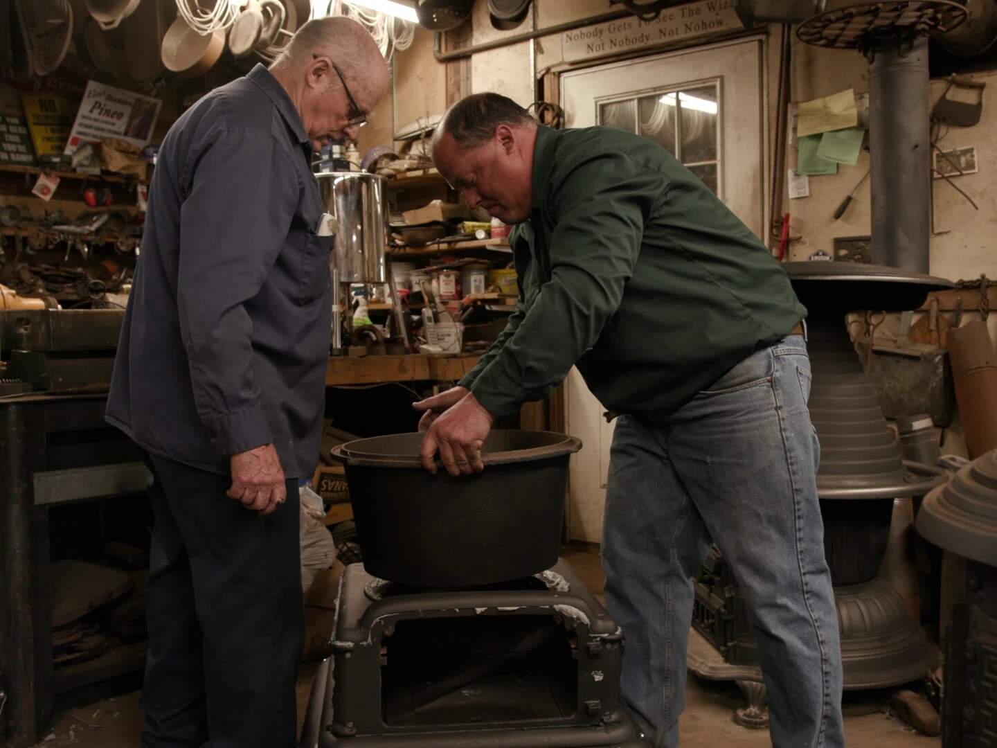 Emory Pineo (left), owner/operator of the Antique Stove Hospital repairing oven in workshop with son Brandon (right). (Mike Jones/Ocean State Media)