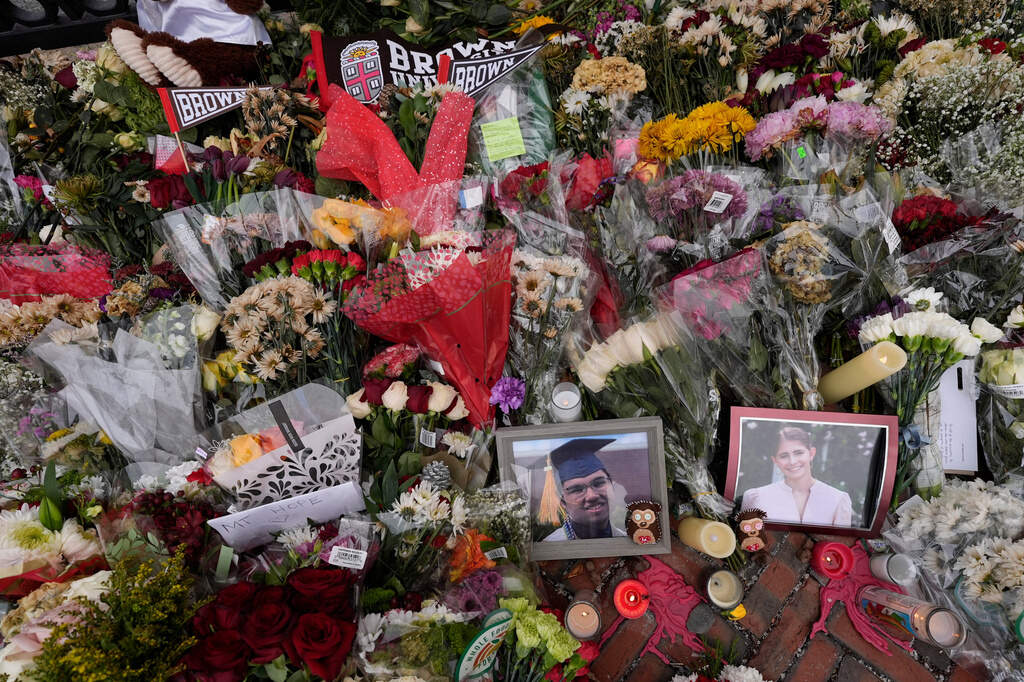 Photos of Brown University shooting victims Mukhammad Aziz Umurzokov, left, and Ella Cook, are seen amongst flowers at a makeshift memorial at the school's Van Wickle Gate, Dec. 17, 2025, in Providence, R.I. (Robert F. Bukaty/ AP, File)