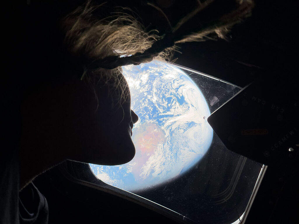 In this image provided by NASA, NASA astronaut and Artemis II mission specialist Christina Koch peers out of one of the Orion spacecraft's main cabin windows, looking back at Earth, as the crew travels towards the Moon on April 4, 2026. (NASA via Getty Images)