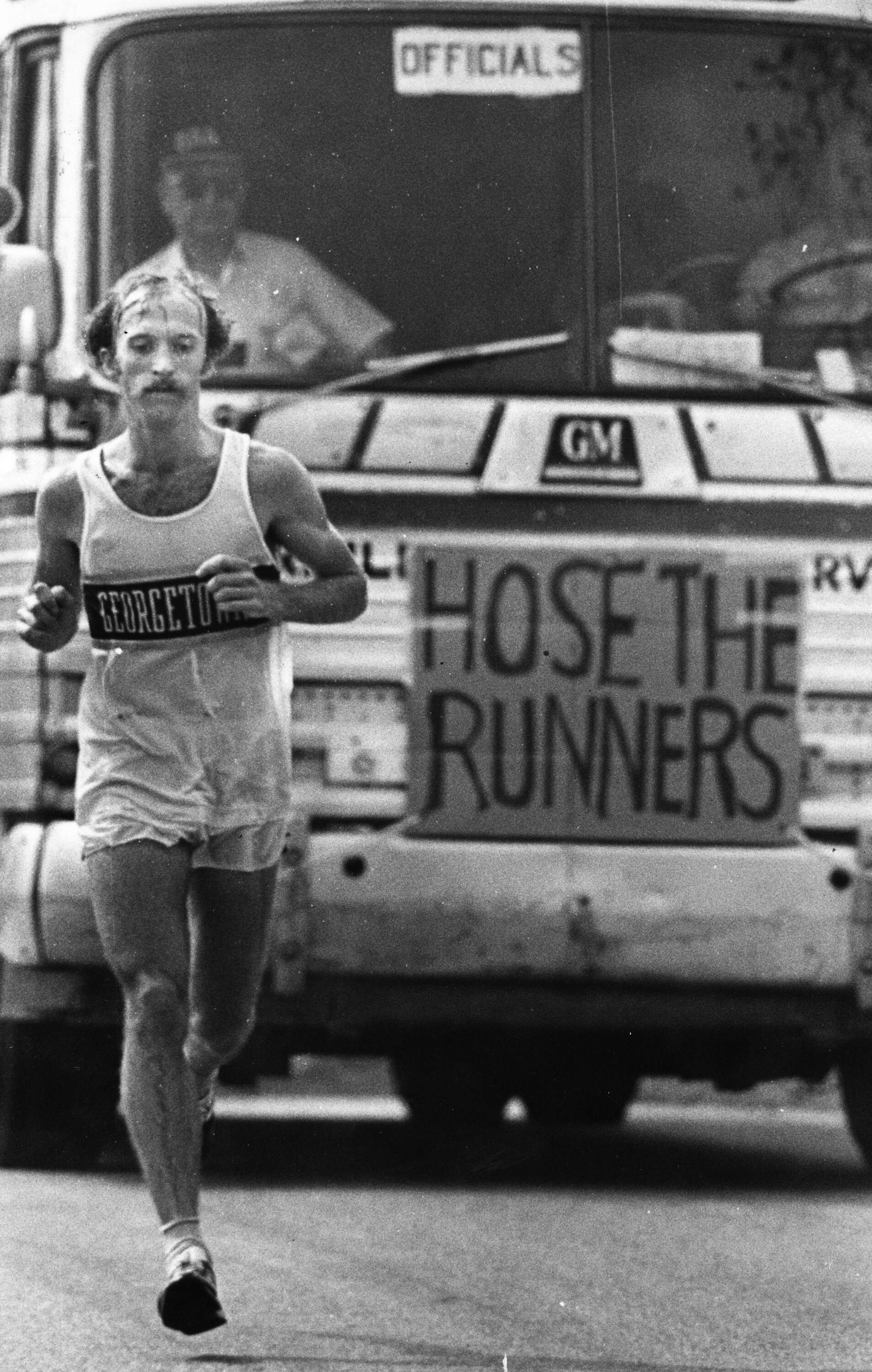 Jack Fultz runs through Newton during the Boston Marathon on April 19, 1976. The official bus behind him has a sign that reads "Hose the Runners." (Frank O'Brien/The Boston Globe via Getty Images)