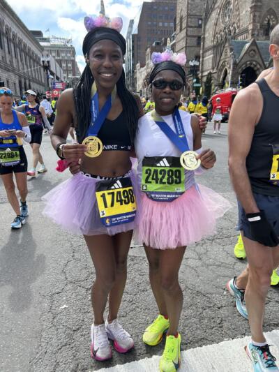 Miki Jameson and her mother Charmaine Jameson in tutus at the finish line of the Boston Marathon. (Martha Bebinger/WBUR)
