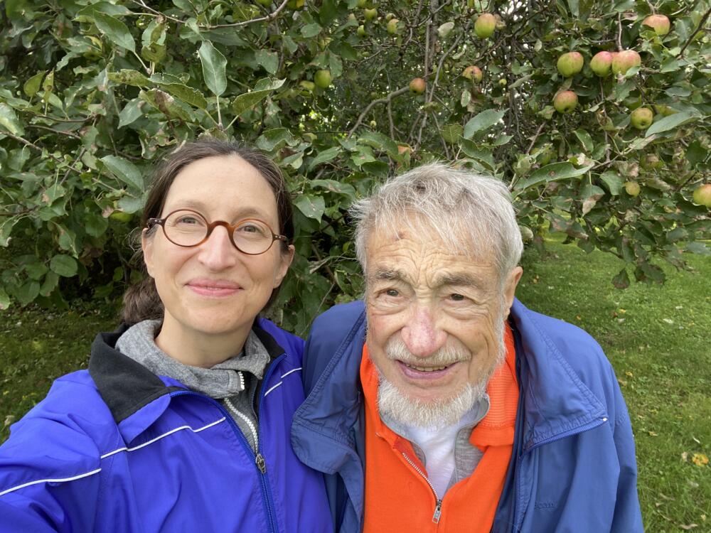 Jennifer Acker stands with her father in front of apple trees. (Courtesy Jennifer Acker)