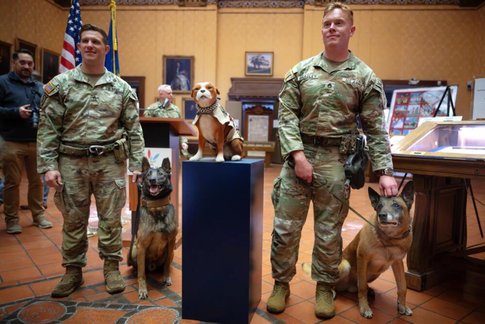 (L-R) Staff Sgt. Trey Shifflett, with his dog Victor, and Staff Sgt. Ian Bradley, with his dog Gandolf, stand with Sgt. Stubby replica for photographers after the ceremony at the Connecticut State Library. (Mark Mirko/Connecticut Public)