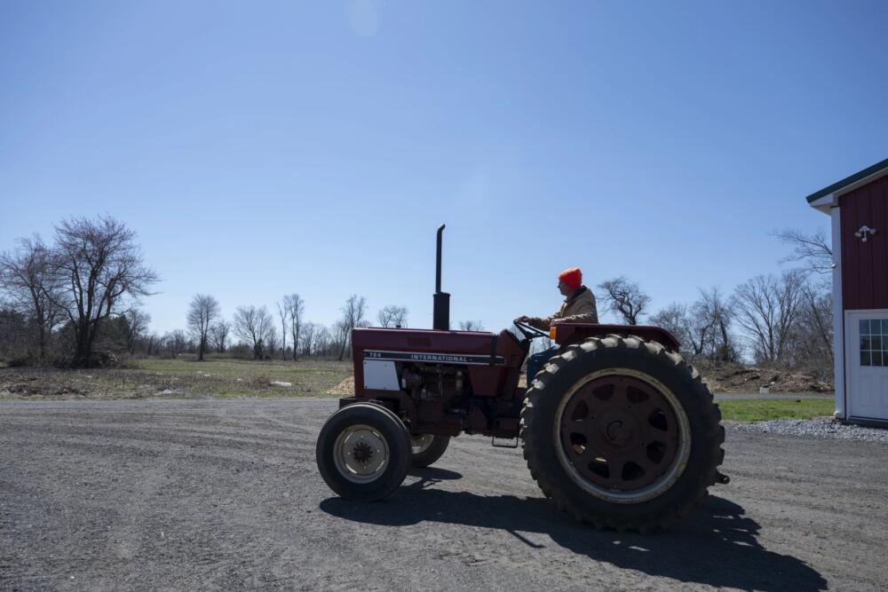 Farmer Lars Demander operates a tractor at Clover Nook Farm barn. (Raquel C. Zaldívar/New England News Collaborative)