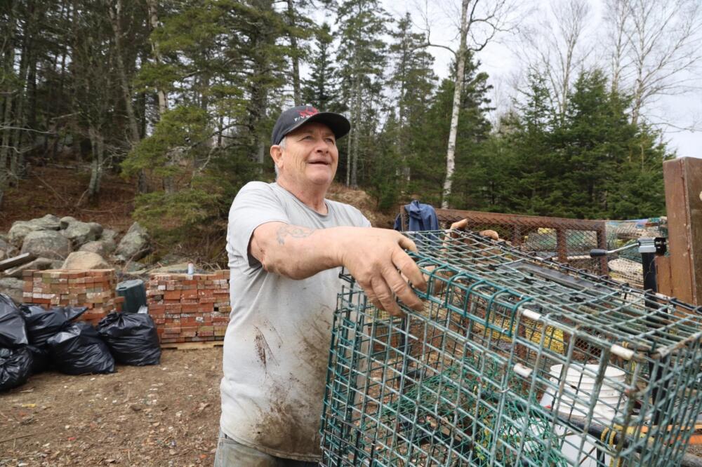 Curt Bryant hands over a trap that's ready to be crushed. Bryant is part of a group of more than a dozen fishermen who are hauling, processing and recycling abandoned fishing traps on Vinalhaven. (Tulley Hescock/Maine Public)
