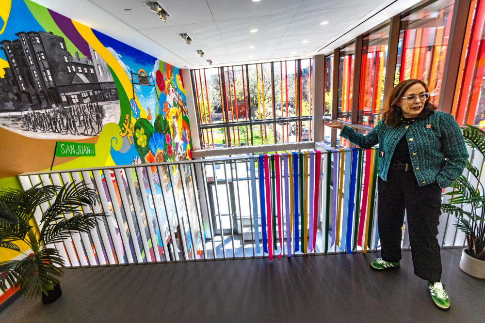 From a balcony on the second floor, CEO of Inquilinos Boricuas en Acción Vanessa Calderón-Rosado presents a mural painted by Alvin "Acóma" Colón inside La CASA's entryway. (Jesse Costa/WBUR)