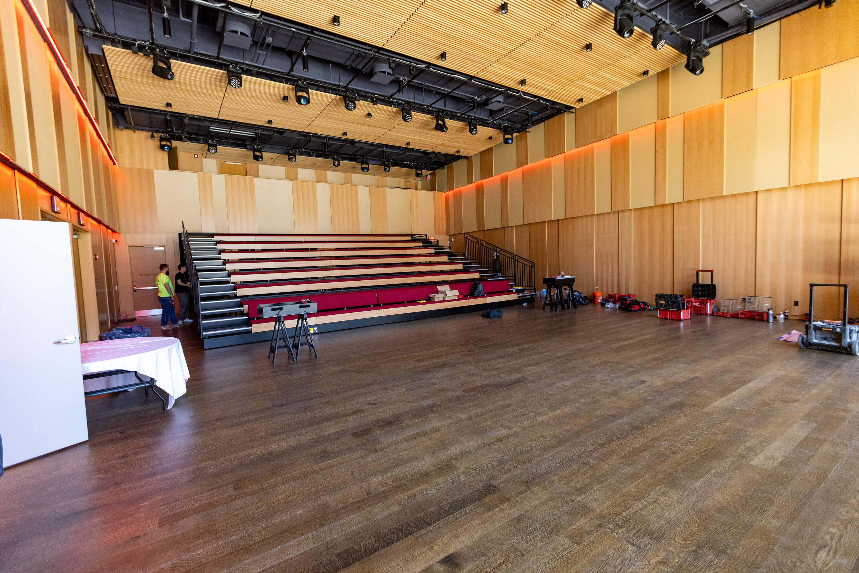 Contractors put the finishing touches on the retractable seating in the La CASA multipurpose event space. (Jesse Costa/WBUR)