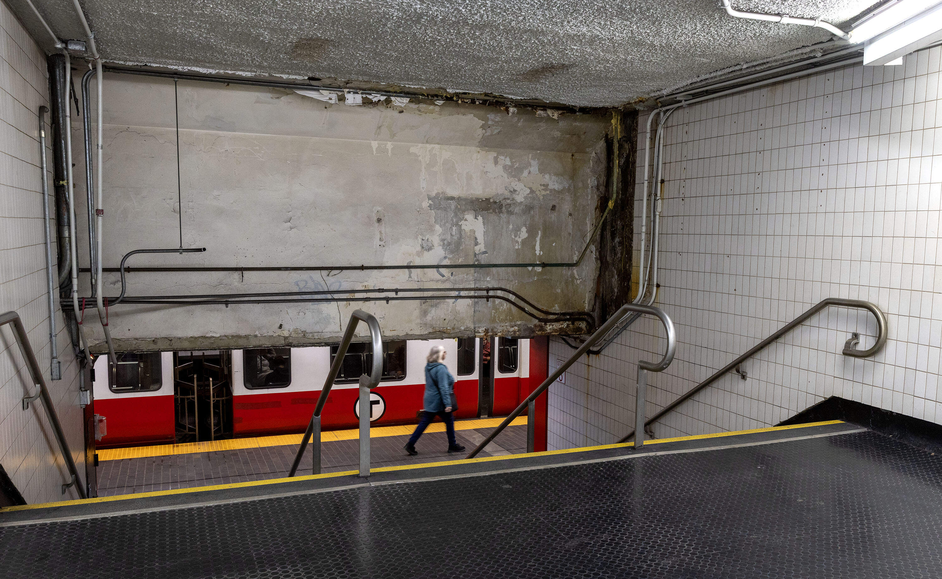 Paint peels from the ceiling by a wall in need of some paint, at the MBTA's Downtown Crossing station. (Robin Lubbock/WBUR)