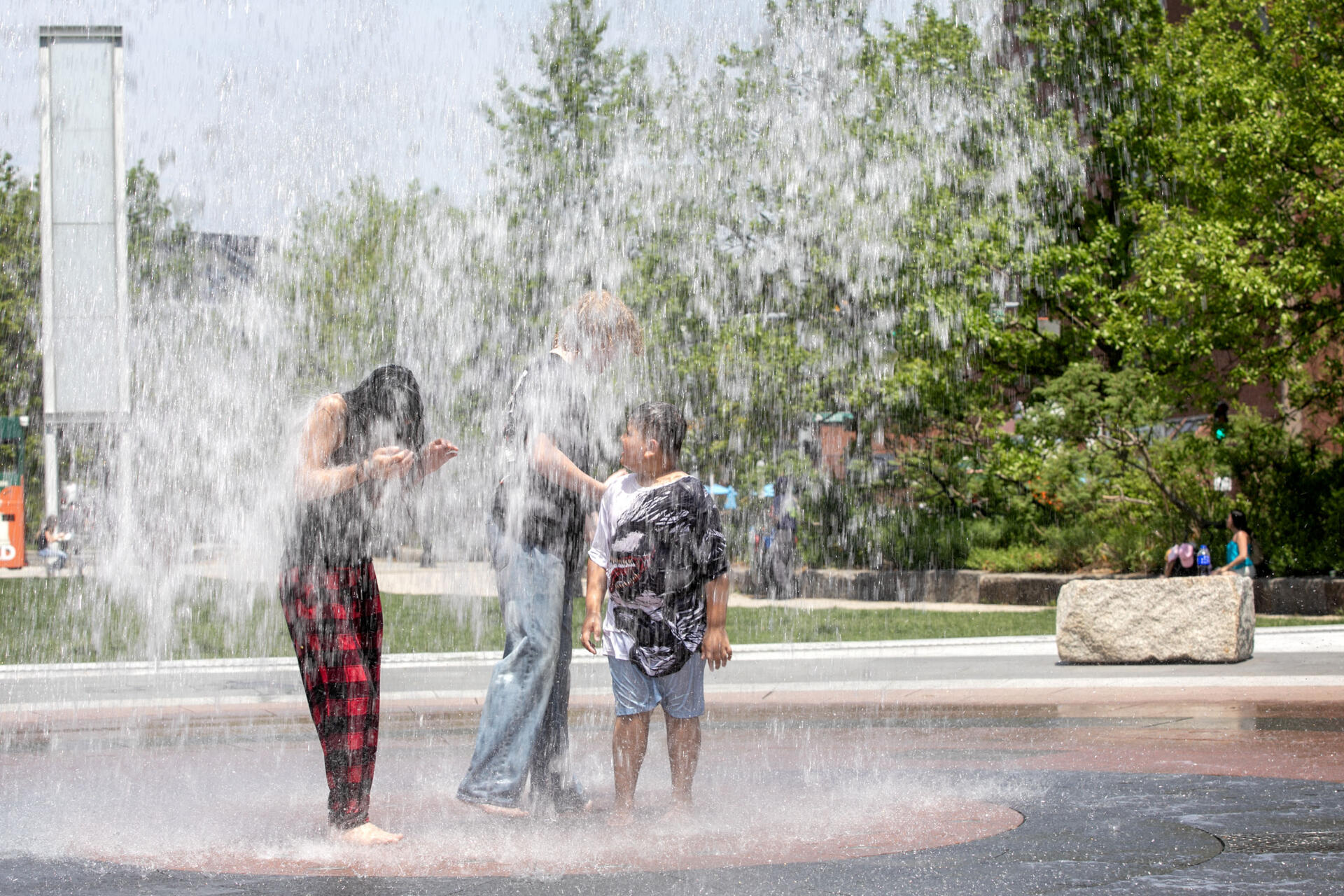 Visitors to the Rose Kennedy Greenway cool off in the Rings Fountain as temperatures in Boston soar into the 90s. (Robin Lubbock/WBUR)