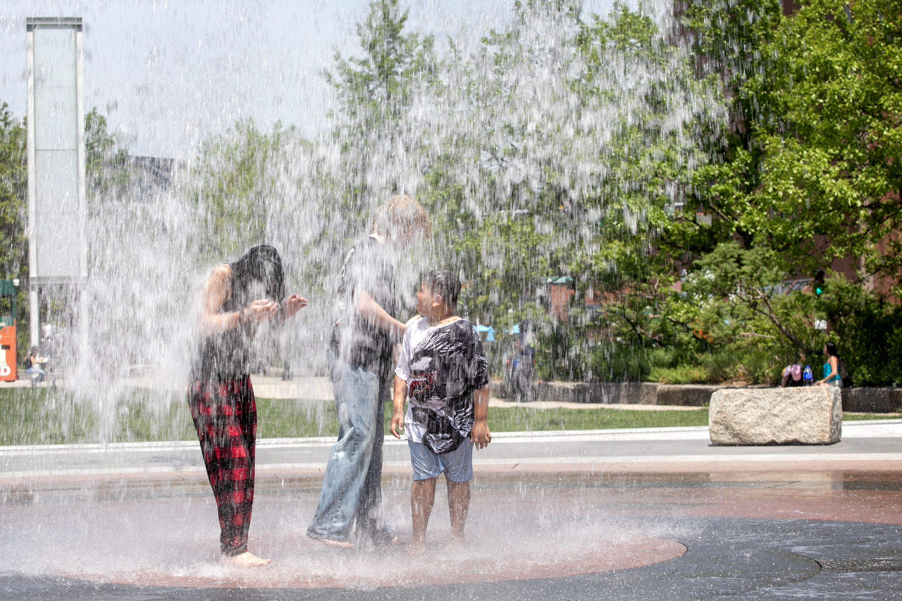 Visitors to the Rose Kennedy Greenway cool off in the Rings Fountain as temperatures in Boston soar into the 90s. (Robin Lubbock/WBUR)