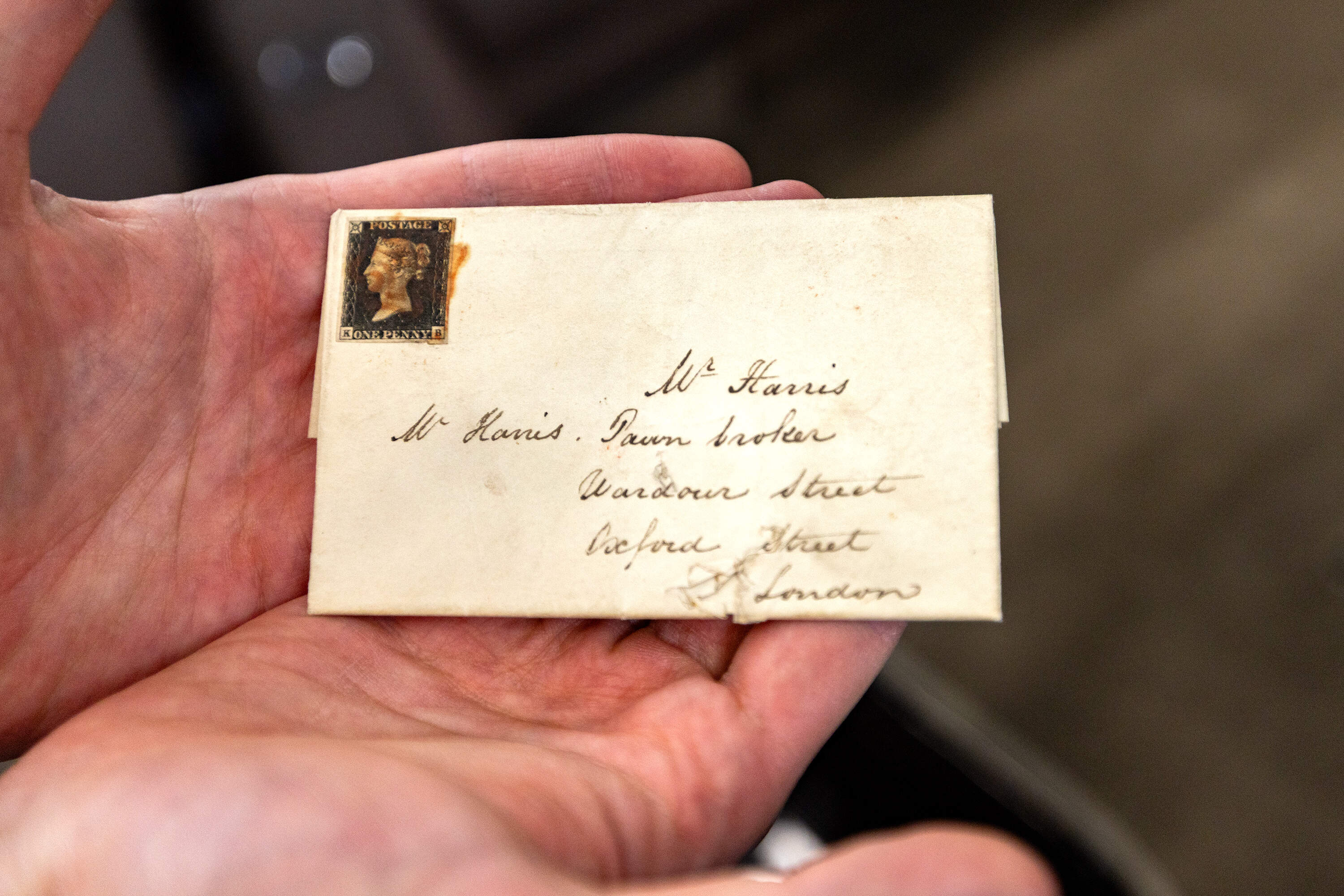 Alex Haimann holds a letter with the very first adhesive stamp with Queen Victoria from 1840. (Jesse Costa/WBUR)