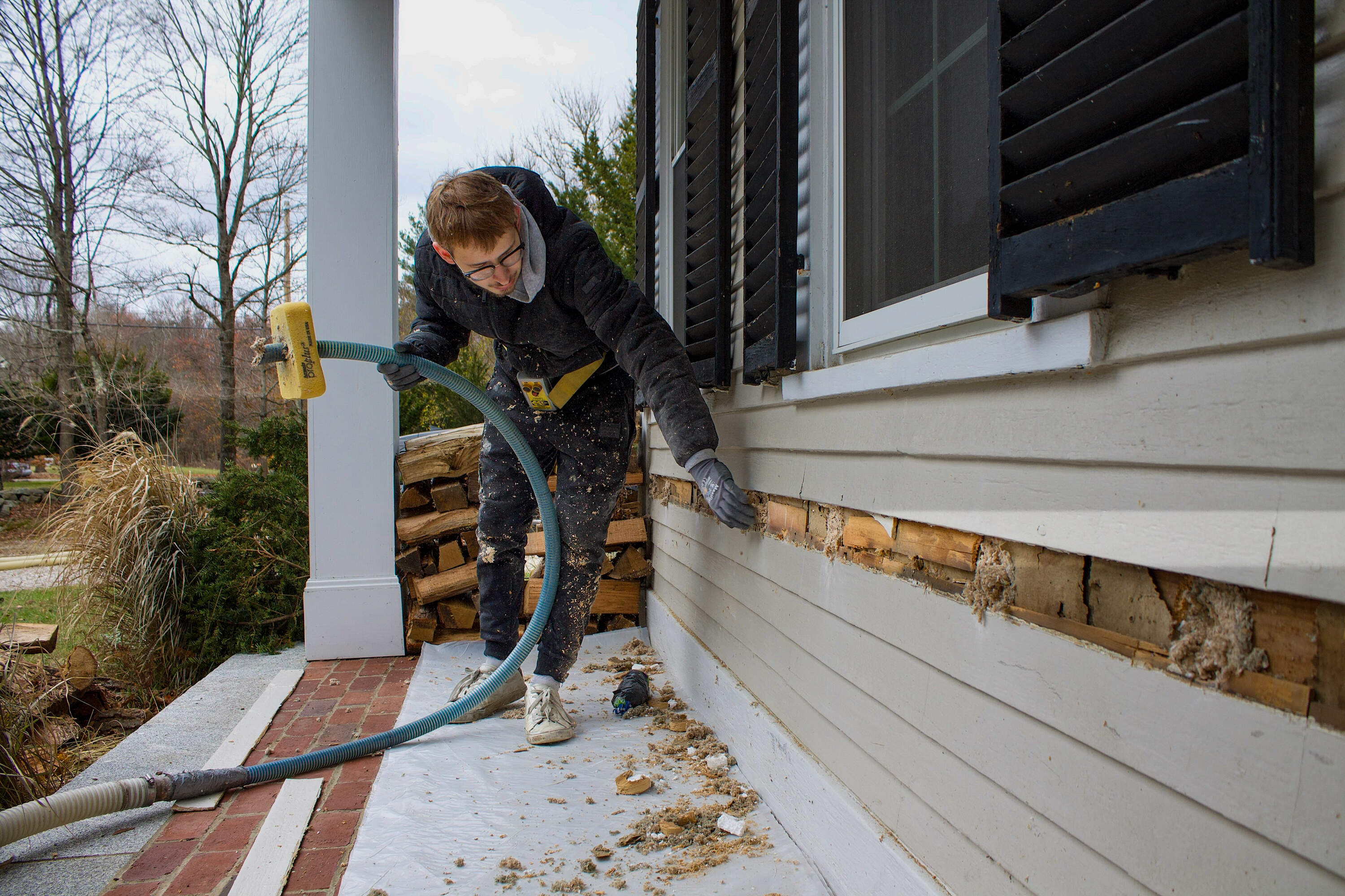 A Mass Save contractor blows insulation into a home in Holliston, Mass. (Miriam Wasser/WBUR)