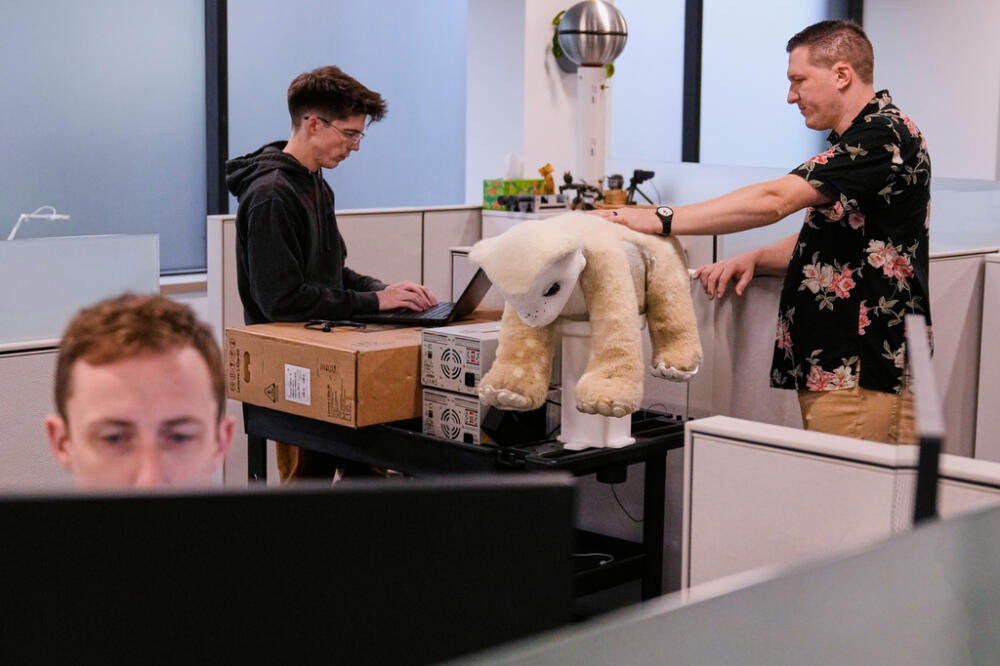 Software engineer Colin Soguero, standing at left, and creative director Morgan Pope, right, work on an AI pet robot, prior to a demonstration in Woburn. (Charles Krupa/AP)