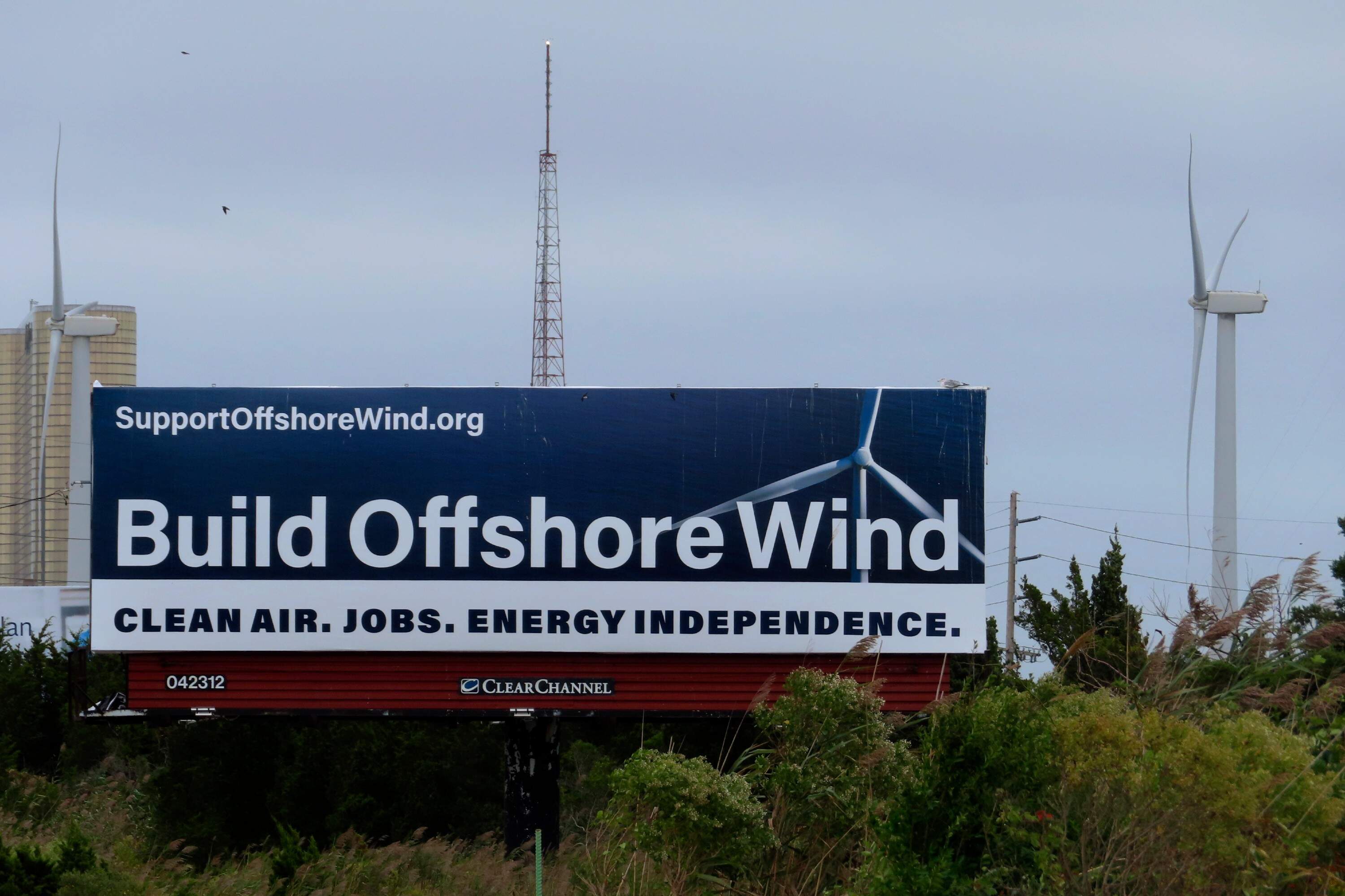 In this Sept. 18, 2024, file photo, a billboard supporting offshore wind power projects sits on a roadside near land-based wind turbines in Atlantic City, N.J. (Wayne Parry/AP)