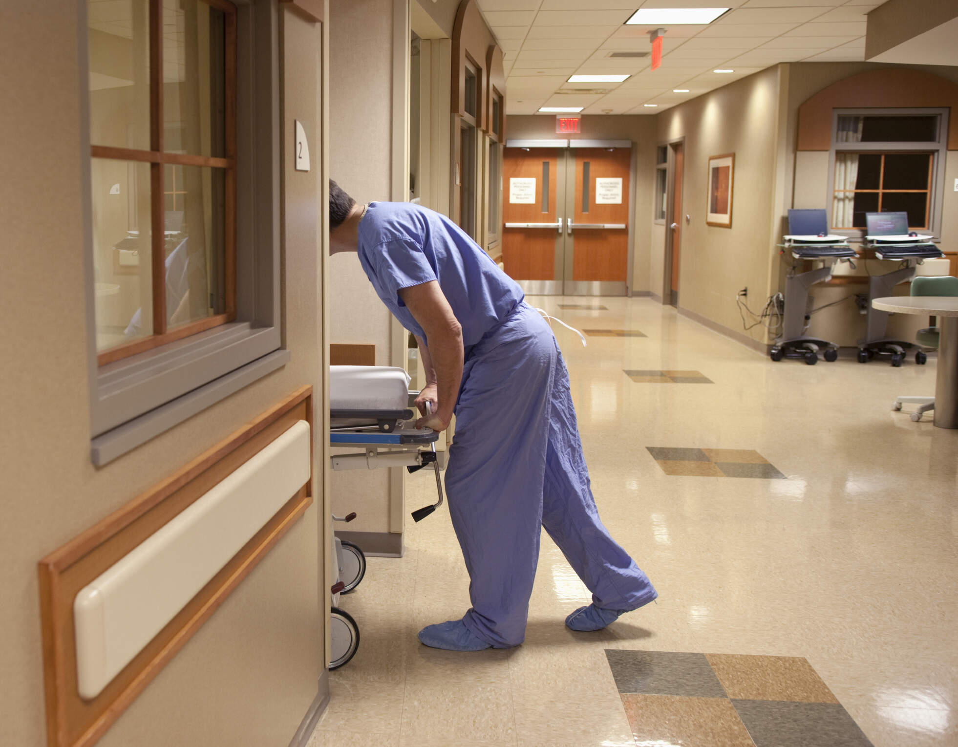 A healthcare worker rolls a patient gurney into a patient room. (Getty Images)