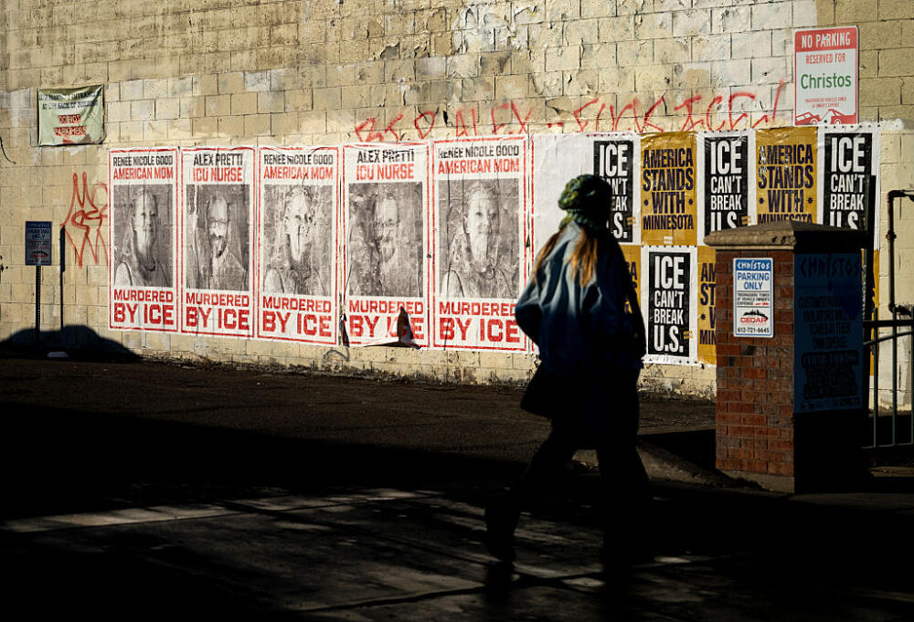 A person walks by signs memorializing Renee Good and Alex Pretti on February 12, 2026 in Minneapolis, Minnesota. Good and Pretti were both shot and killed by federal immigration agents in January. (Stephen Maturen/Getty Images)