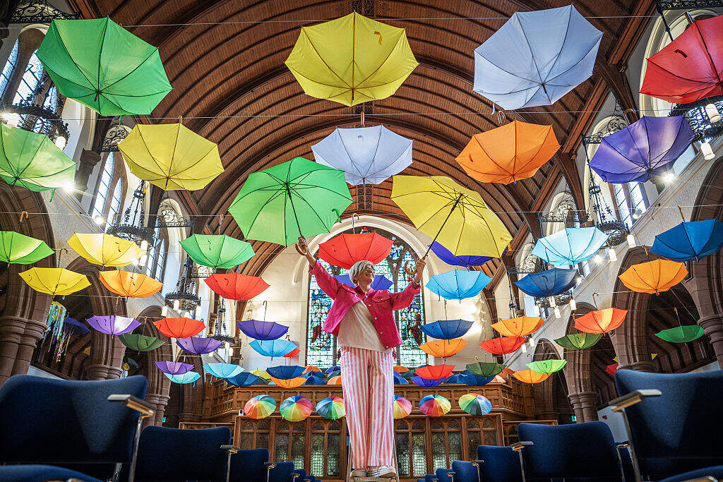 Event organizer Kerry Watt stands underneath some of the 100 umbrellas suspended from Morningside Parish Church's ceiling, to create a colorful canopy on display during the Edinburgh Umbrella Festival on Friday May 29, 2026. (Jane Barlow/PA Images via Getty Images)