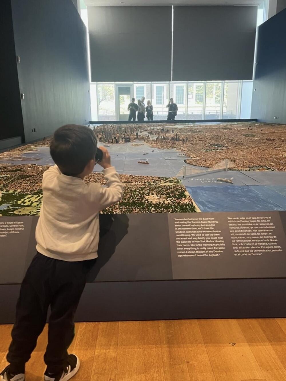 Boy uses binoculars to take in Joe Macken's model at the Museum of the City of New York. (Robin Young/Here &amp; Now)