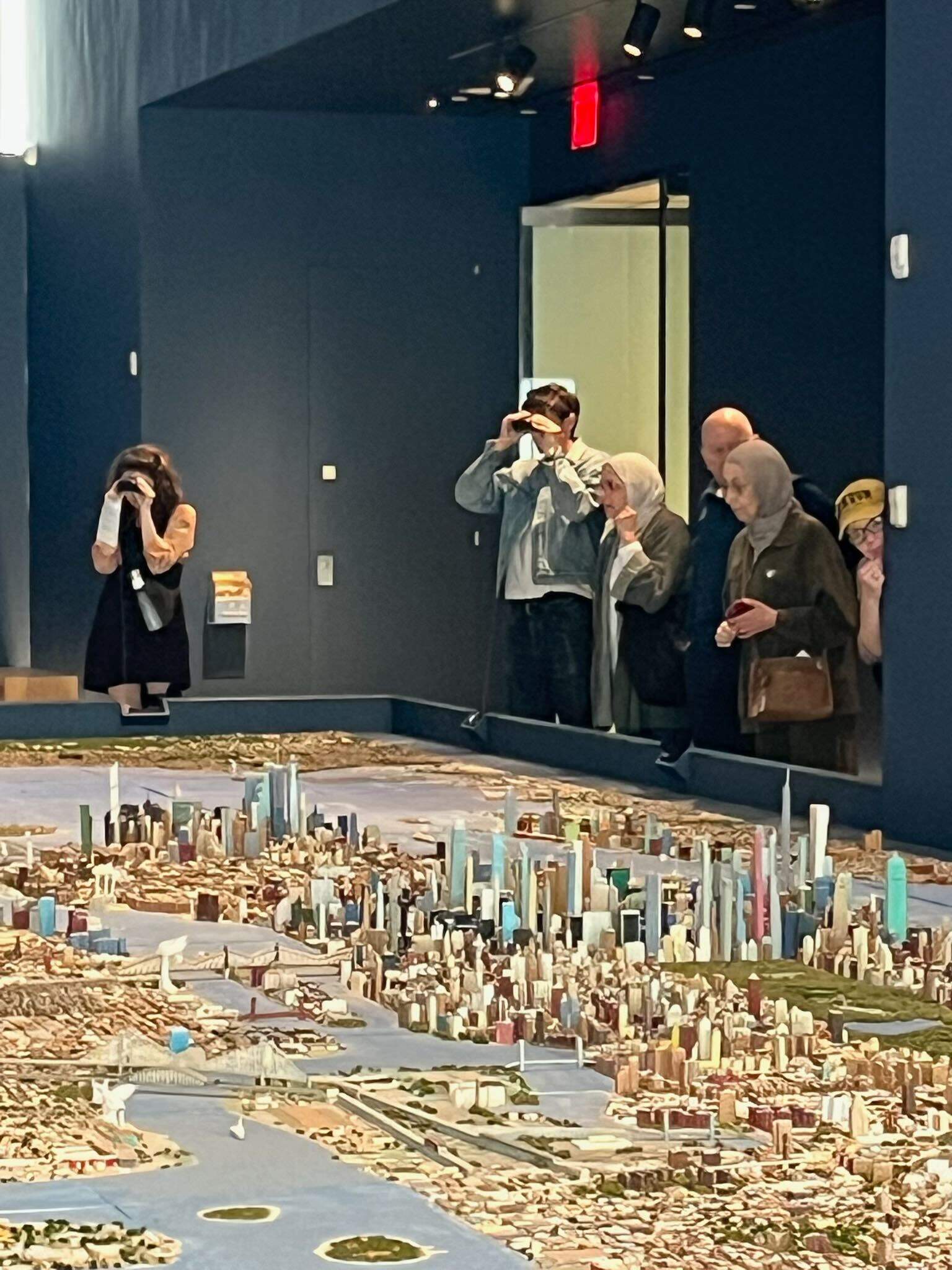 Exhibit goers look over "He Built This City" by Joe Macken. (Karyn Miller-Medzon/Here &amp; Now) 