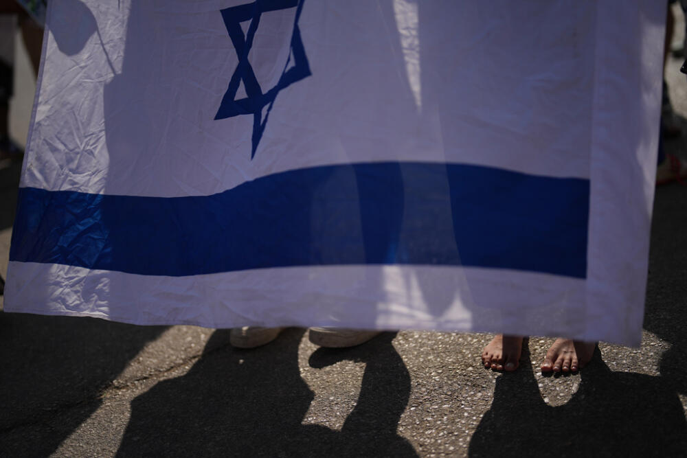 People stand behind an Israeli flag as they wait outside Beilinson Hospital in Petah Tikva, Israel. (AP Photo/Francisco Seco)