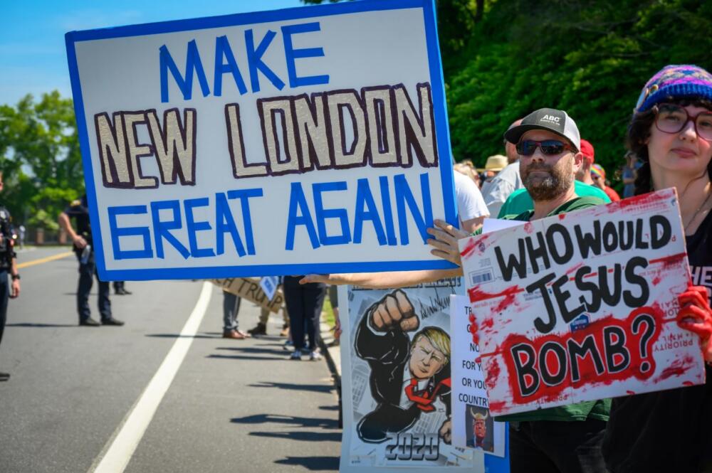 An estimated 100 protesters — including some military veterans — lined the sidewalks of a major intersection in New London Wednesday morning, pausing their anti-Trump chants to clap and cheer for the U.S. Coast Guard graduates as they headed to the ceremony. (Rachel Iacovone/Connecticut Public)