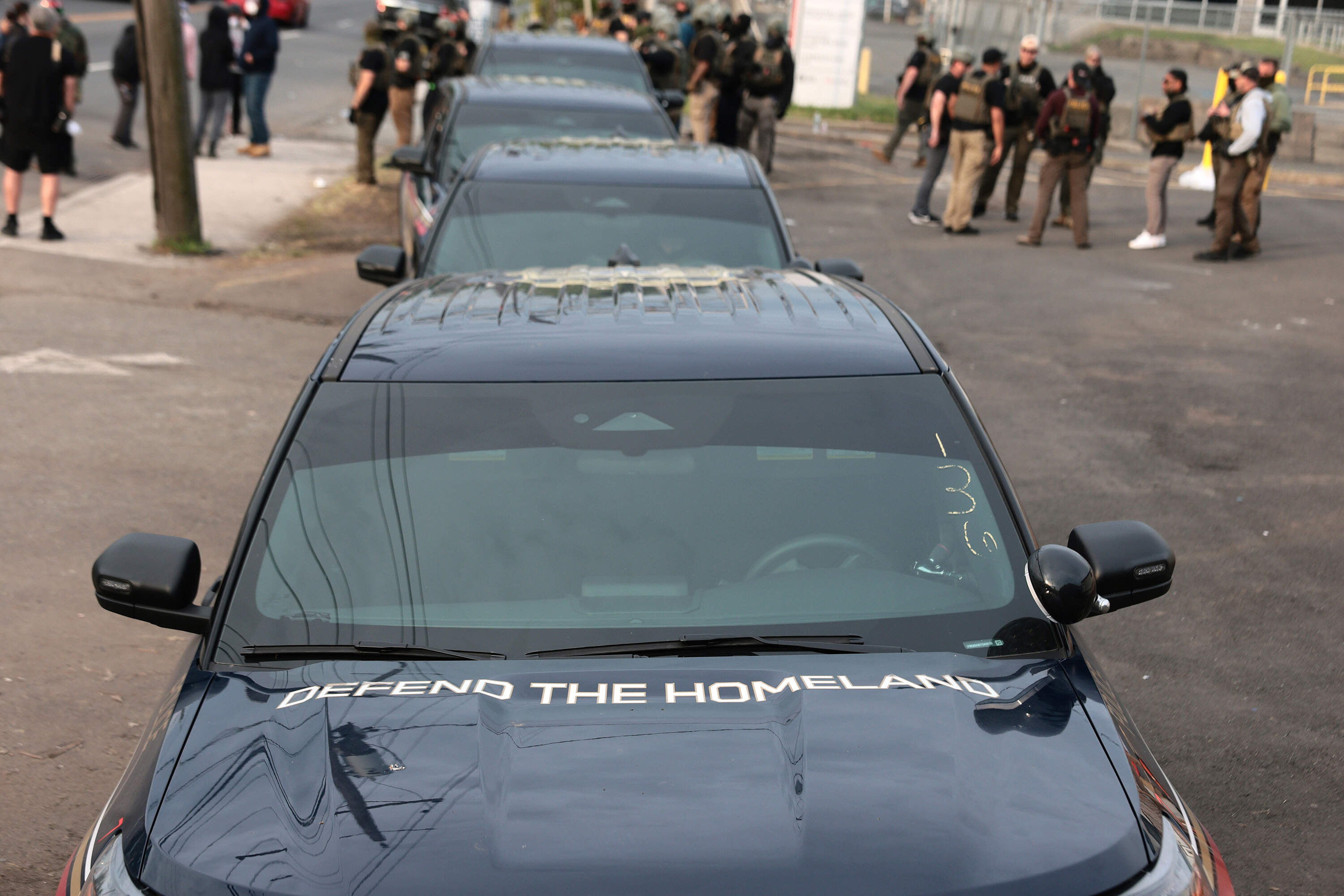 ICE vehicles are parked as agents stand guard in front of protesters outside Delaney Hall, which is being used as a detention center, on May 27 in Newark, New Jersey. (Michael M. Santiago/Getty Images)